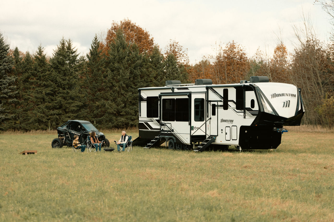 Grand Design Momentum with family sitting in front of it