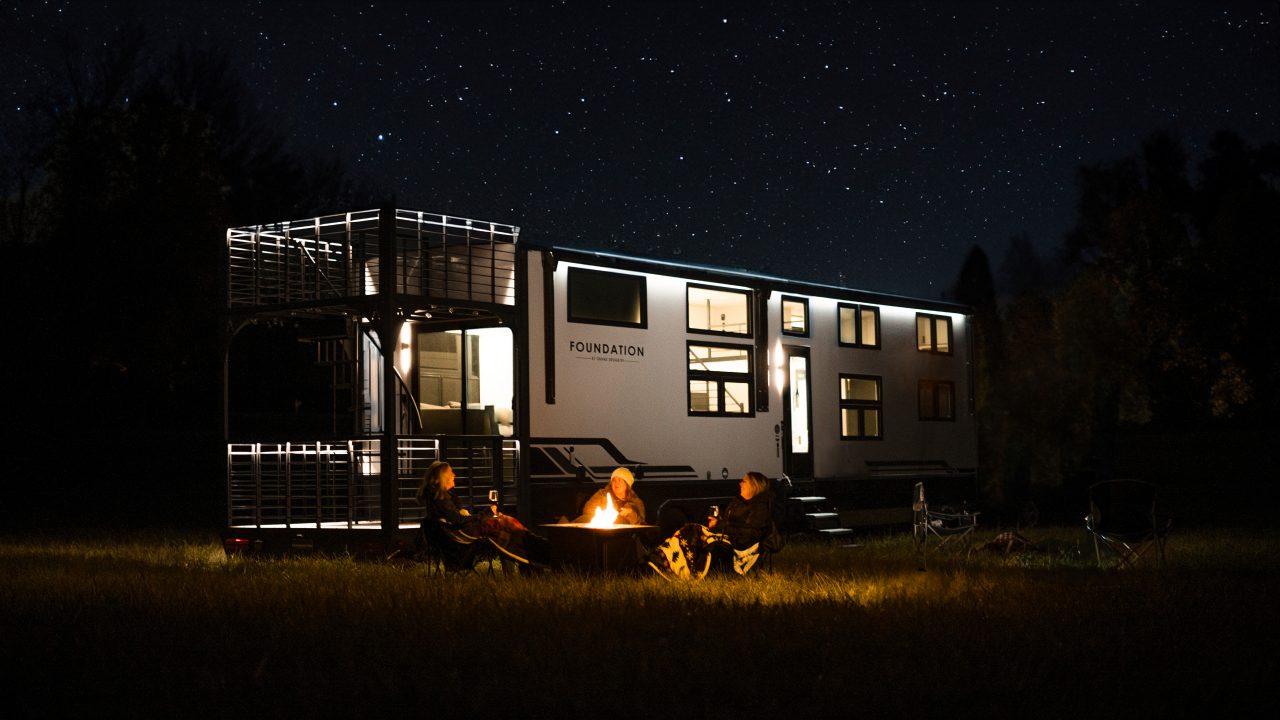 Three women by a campfire and an RV